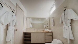 A modern bathroom with a wooden vanity, a toilet, and two robes hanging on hooks. - Noma Hotel And Rooftop (Cali)