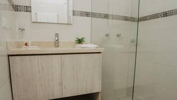 Ein modernes Badezimmer mit einer Duschkabine aus Glas, einem Holzausziehtisch und einem Spiegel über dem Waschbecken.