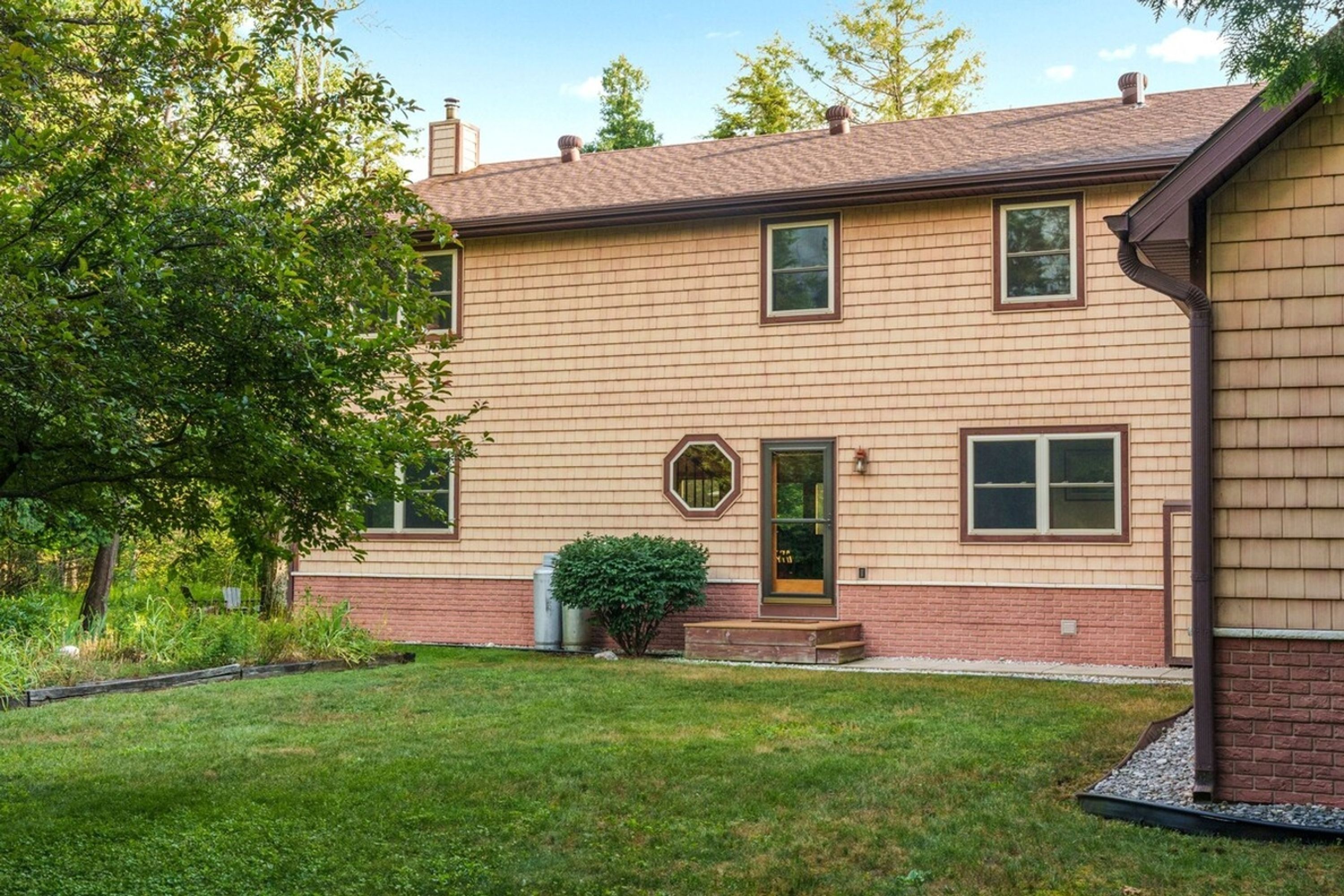 A two-story house with a brick foundation and a wooden exterior.