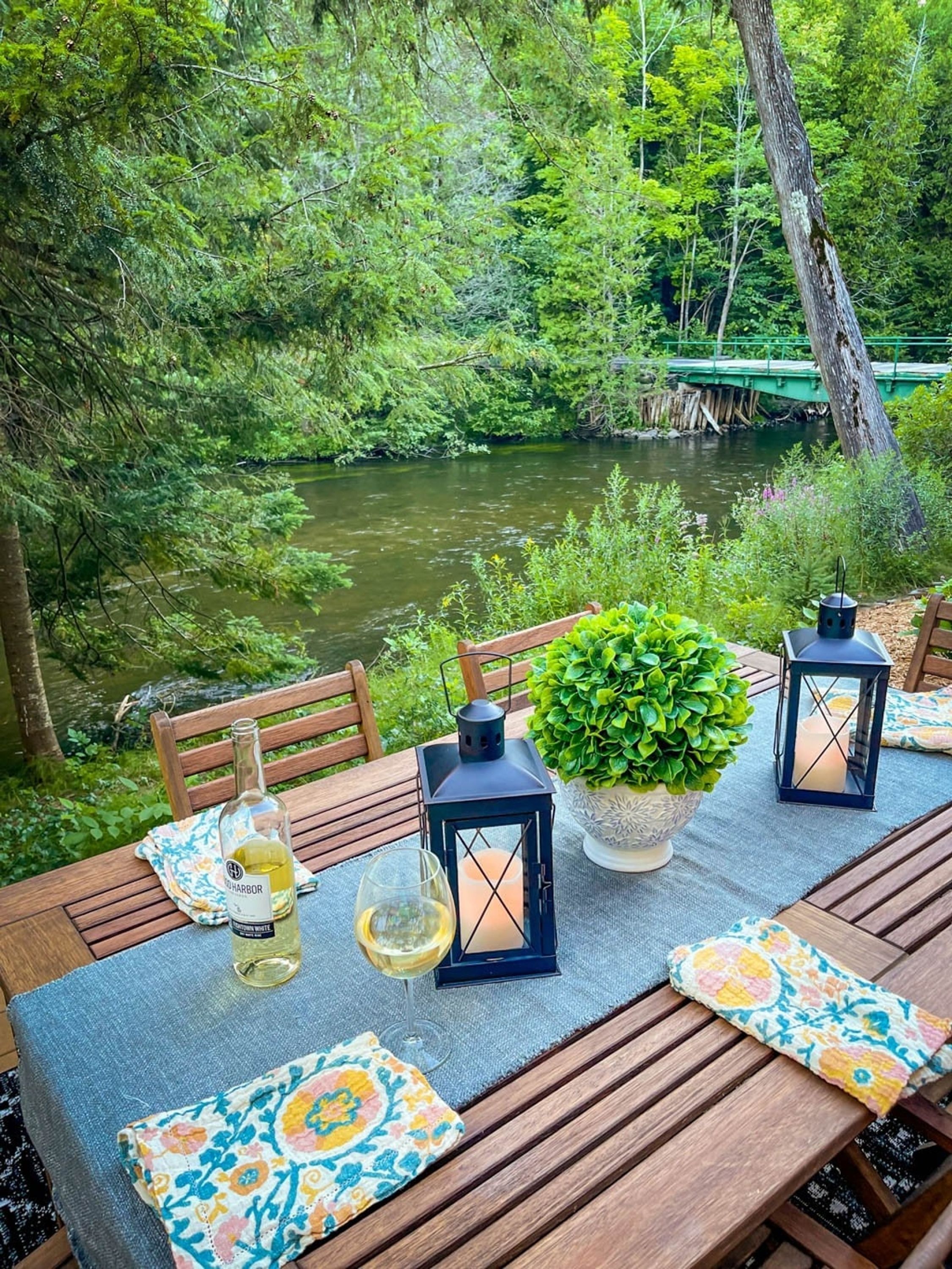 Mesa al aire libre con una botella de vino blanco, copas y un farol.
