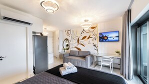 Une chambre d’hôtel moderne équipée d’un lit, d’un bureau, d’un canapé et d’une télévision.