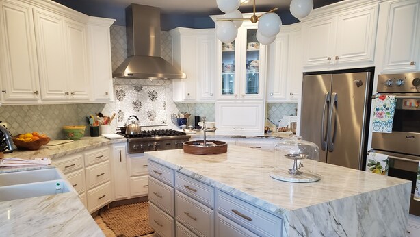 A modern kitchen with white cabinetry, a marble island, stainless steel appliances, and a decorative backsplash. - Charming 4-bedroom house in lovely Los Angeles with AC (Los Angeles)