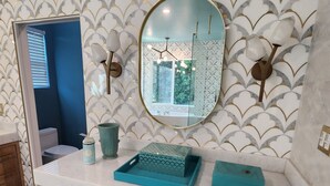 A bathroom with a marble floor, a wooden vanity with drawers, a mirror, and a patterned wall. - Charming 4-bedroom house in lovely Los Angeles with AC (Los Angeles)