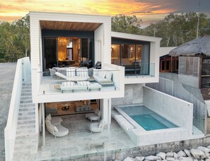 A modern multi-level house with a glass balcony, outdoor seating, and a swimming pool. - 
Dacha Prestige (Nelly Bay)