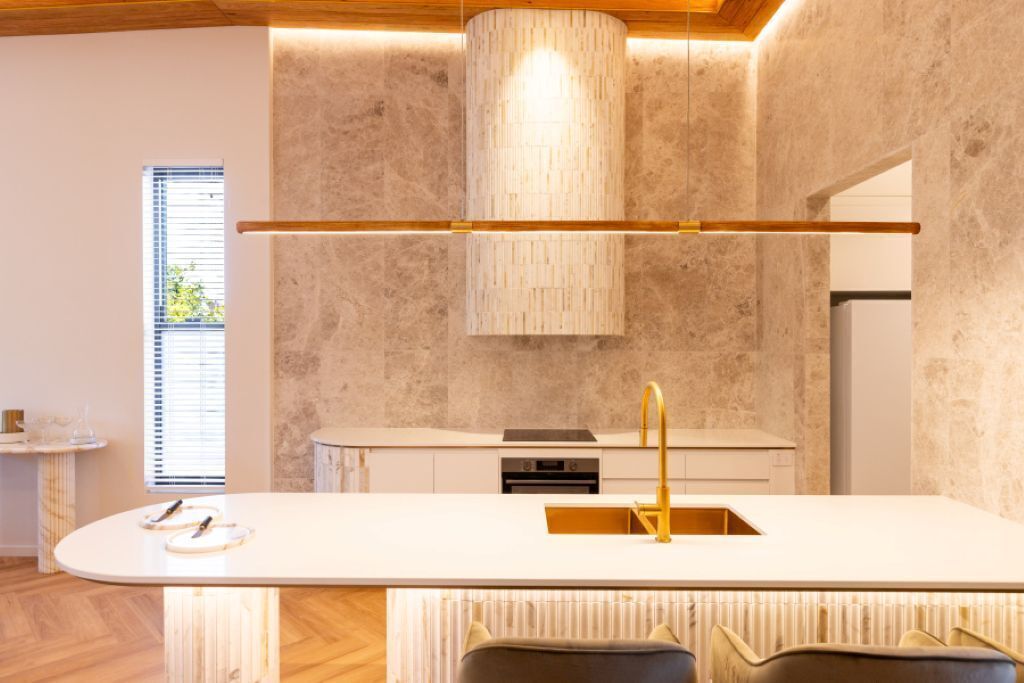 A modern kitchen with a central island, a built-in oven, and a pendant light.