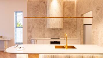 A modern kitchen with a central island, a built-in oven, and a pendant light.