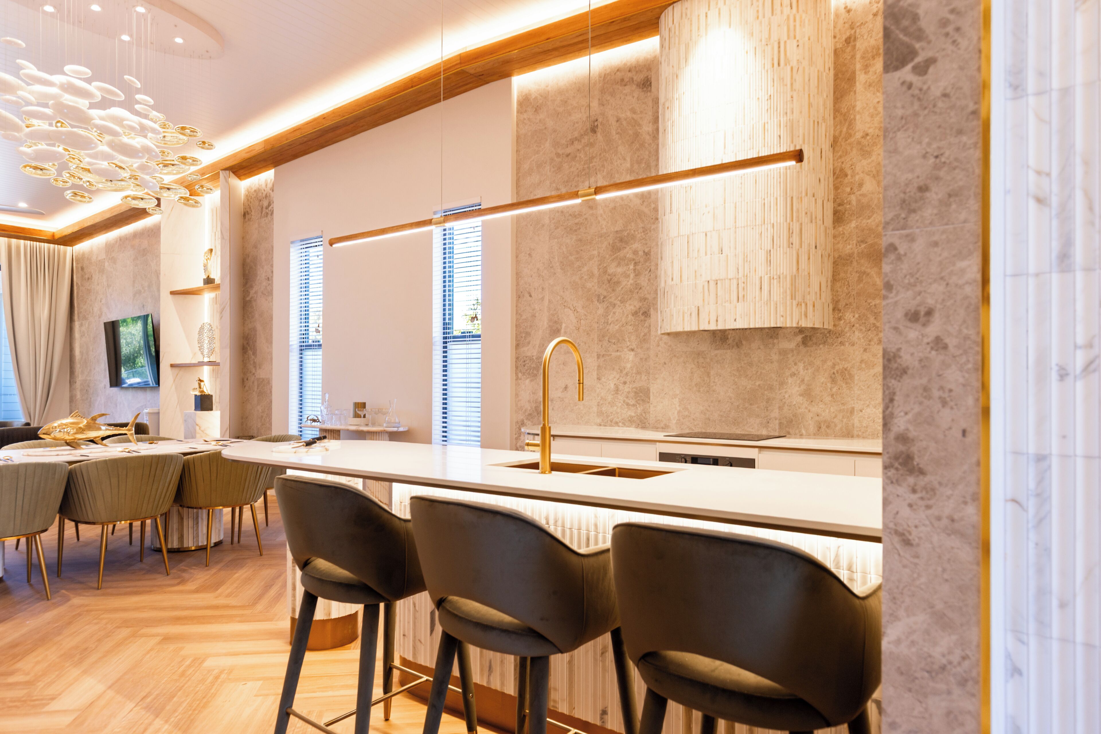 A modern kitchen with a central island, bar stools, and pendant lighting.