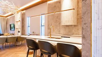 A modern kitchen with a central island, bar stools, and pendant lighting.
