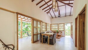 Une pièce spacieuse avec une table et des chaises en bois, de grandes fenêtres et un ventilateur de plafond.