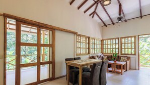 Une pièce spacieuse avec de grandes fenêtres, une table à manger en bois et un canapé.
