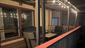 A deck area with a wooden floor, a red railing, and a seating area with a chair and a table. - Newly Renovated Lakefront w/Dock (Bethel Island)