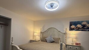A bedroom with a bed, bedside tables, a ceiling fan, and a wall with a floral painting. - Newly Renovated Lakefront w/Dock (Bethel Island)