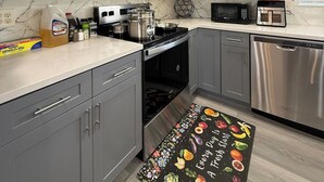 A modern kitchen with grey cabinets, stainless steel appliances, and a marble backsplash. - Newly Renovated Lakefront w/Dock (Bethel Island)