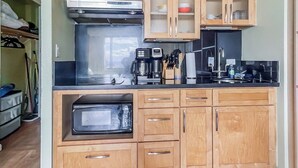 A kitchen with wooden cabinets, a microwave, a coffee maker, and a toaster. - Charming Twin-Joined Studio with Plentiful Space (Honolulu)