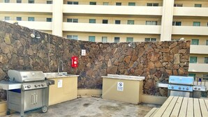 An outdoor patio with a stone wall, a grill, a sink, and a table. - Charming Twin-Joined Studio with Plentiful Space (Honolulu)