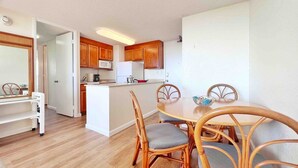 Una cocina compacta con muebles de madera, un microondas y un refrigerador.