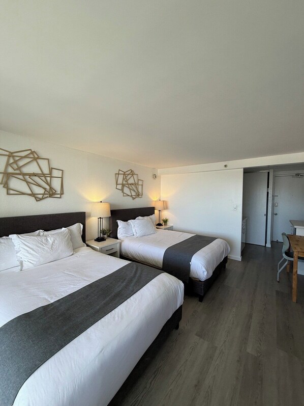 A hotel room with two beds, a desk, and a chair.