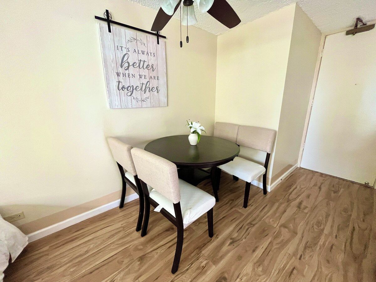 A dining area with a round table, four chairs, and a wall-mounted sign.