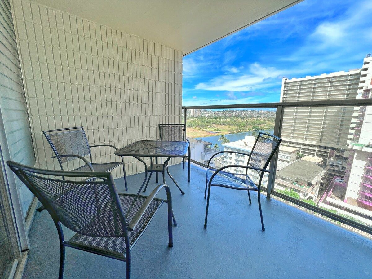 Un balcon avec une table et des chaises, une vue sur le paysage urbain et un bâtiment en arrière-plan.