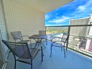 Un balcon avec une table et des chaises, une vue sur le paysage urbain et un bâtiment en arrière-plan.