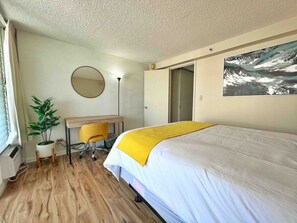 A hotel room with a bed, a desk, a chair, a potted plant, and a large window. - Comfy and Modern Condo By Waikiki! (Honolulu)