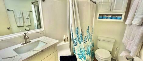 Un baño con lavamanos, inodoro, cortina de ducha y espejo.