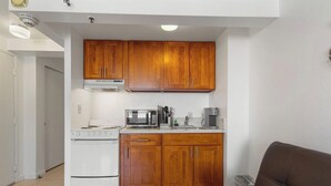 Una cocina compacta con armarios de madera, un microondas, una estufa y una cafetera.