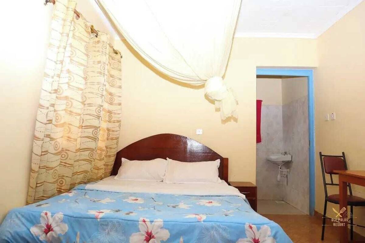 Een slaapkamer met een bed, nachtkastje, stoel en deur naar de badkamer.