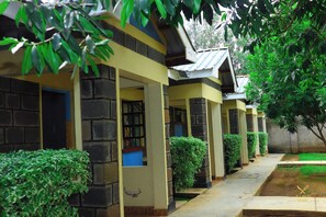 A row of rooms with stone walls and yellow trim, connected by a covered walkway. - Ole Polos Resort Mogotio  (Mogotio)