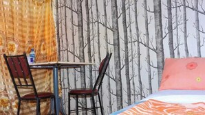A bedroom with a bed, a desk, two chairs, and a wall with a tree pattern. - Ole Polos Resort Mogotio  (Mogotio)