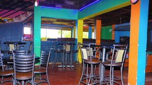A restaurant interior with multiple high tables and chairs, colorful walls, and a tiled floor. - Ole Polos Resort Mogotio  (Mogotio)