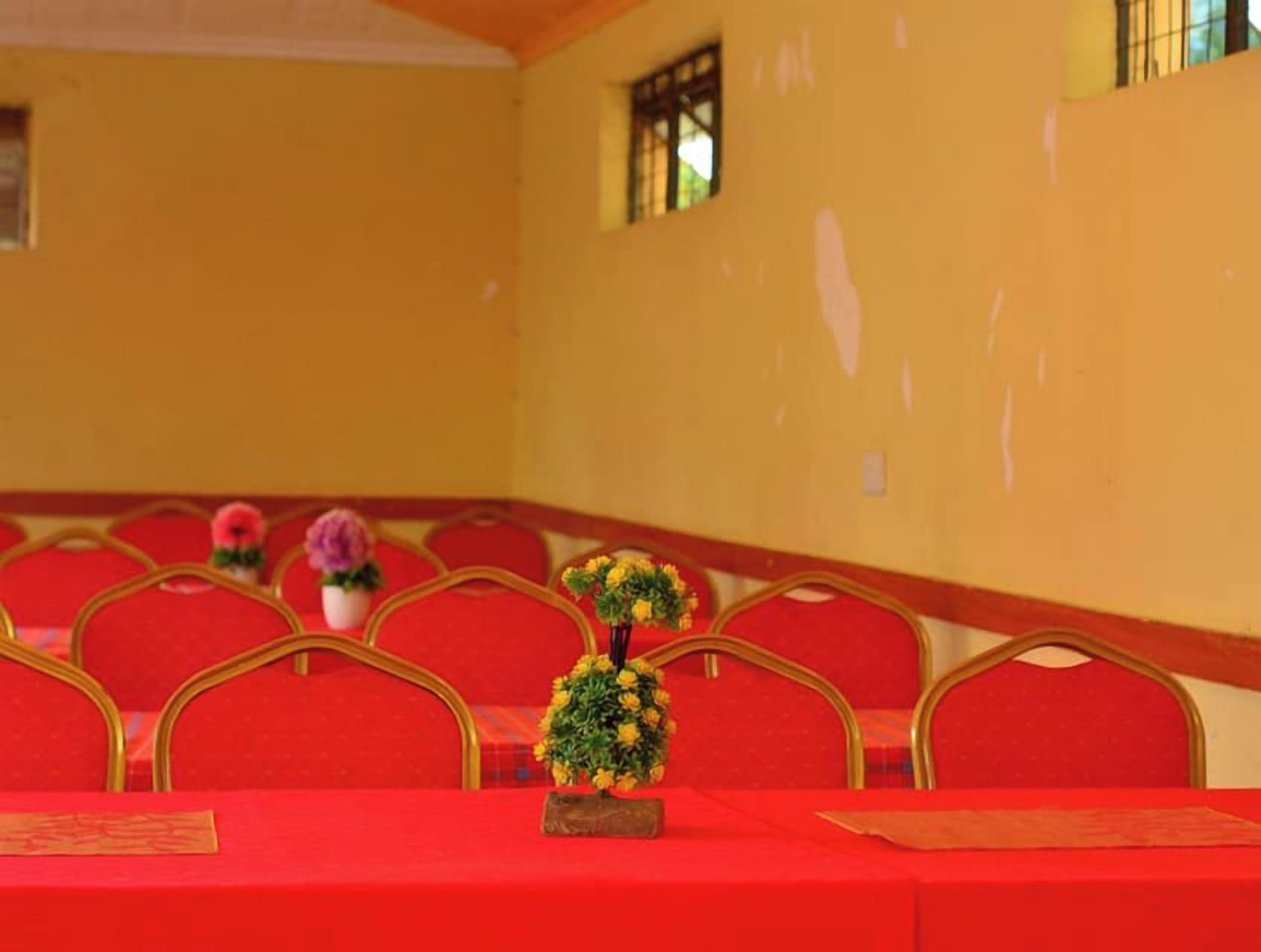 A conference room with red chairs and a table, decorated with small potted plants.