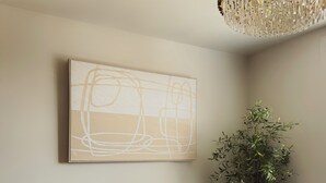 Un salon moderne avec un canapé gris, un grand tableau abstrait, un lampadaire et une plante en pot.