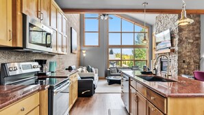 Une cuisine moderne avec des meubles en bois, des appareils en acier inoxydable et une grande fenêtre donnant sur l’extérieur.