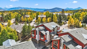 Un quartier résidentiel où les maisons se distinguent par leurs façades rouges et blanches, entourées d’arbres aux couleurs automnales et avec des montagnes en toile de fond.