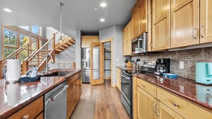 Une cuisine moderne avec des meubles en bois, des appareils en acier inoxydable et un plan de travail en granit.