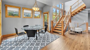 Un intérieur moderne comprenant un coin repas, un escalier et de grandes fenêtres.