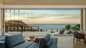 A modern living room with a large view of the ocean and a distant cityscape. - Villa Solara | Panoramic Ocean views & Luxury Mountaun Retreat villa (San Jose del Cabo)