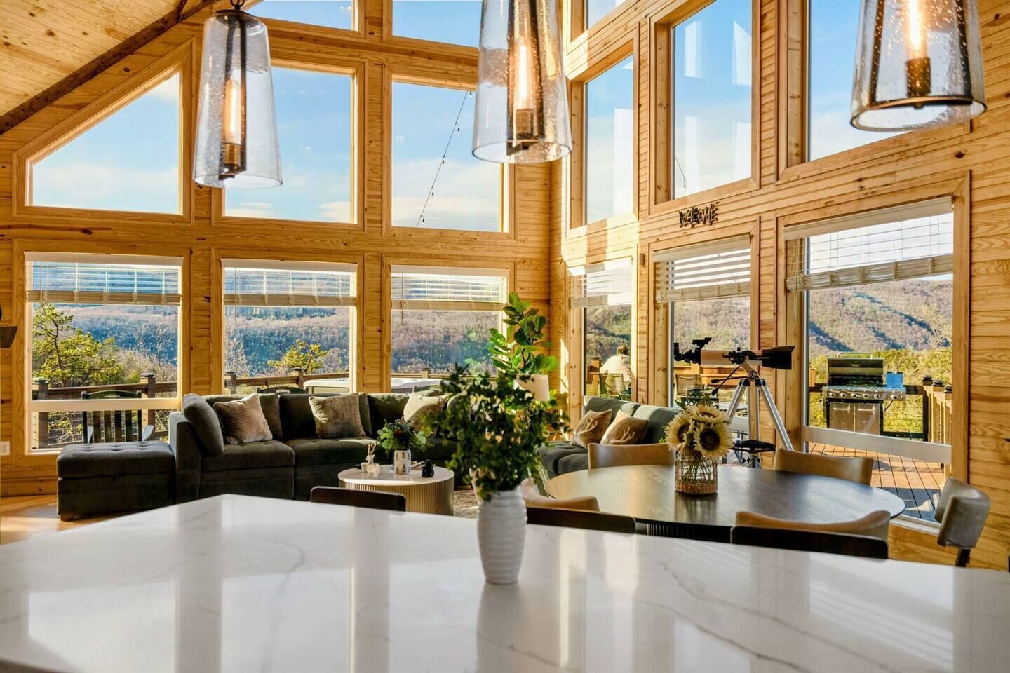 A spacious wooden cabin with large windows, a central seating area, and a dining table.