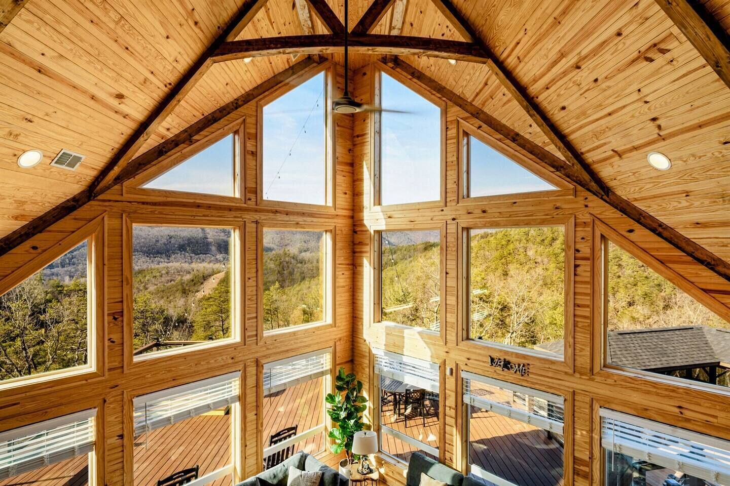A high-ceilinged wooden interior with large windows offering views of a forested landscape.