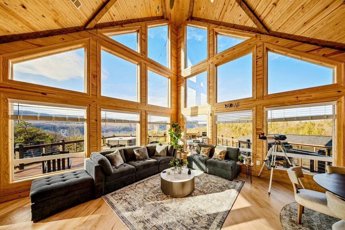 A spacious living room with a large sectional sofa, a coffee table, and a telescope on a tripod.