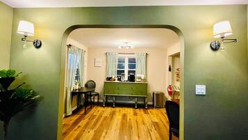 A kitchen with wooden flooring, a green cabinet, and two wall-mounted lamps.