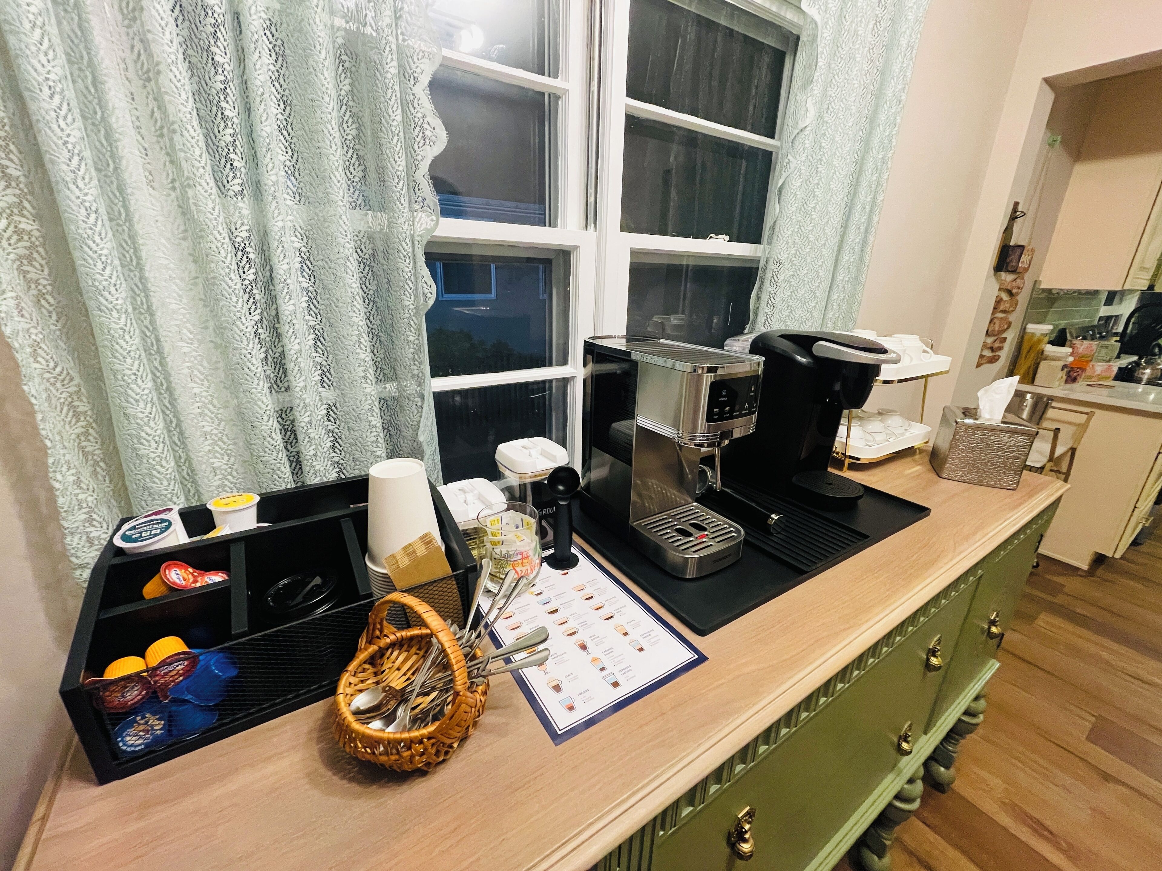 Un comptoir de cuisine avec une machine à café, un panier rempli d’ustensiles et un menu.