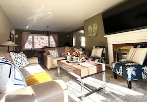 A living room with a sofa, armchairs, a coffee table, and a fireplace.