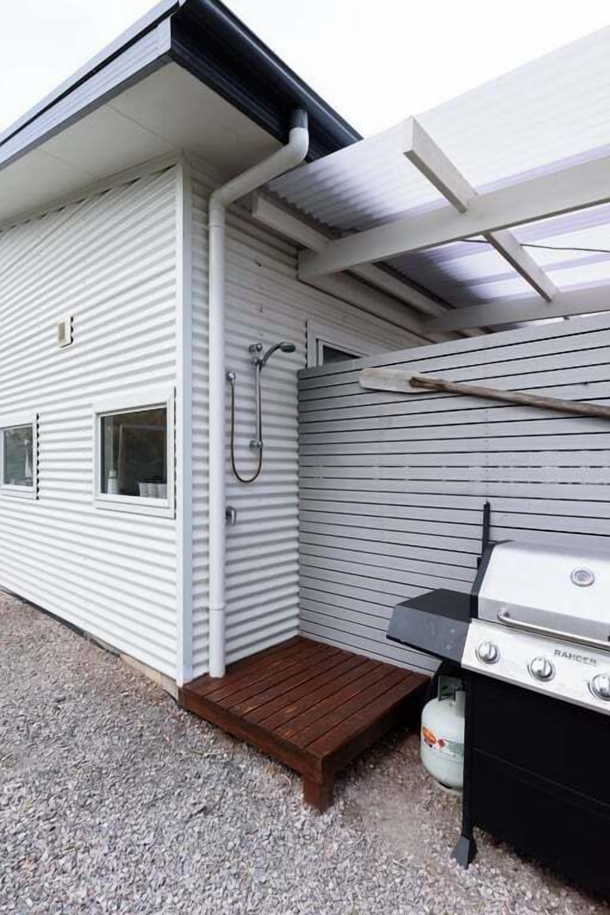 En campingvogn med grill, brusebad og en lille terrasse.