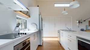 A modern kitchen with white cabinets, a built-in oven, a stove, and pendant lights. - Low Head Coastal Haven: Your Seaside Escape (George Town)