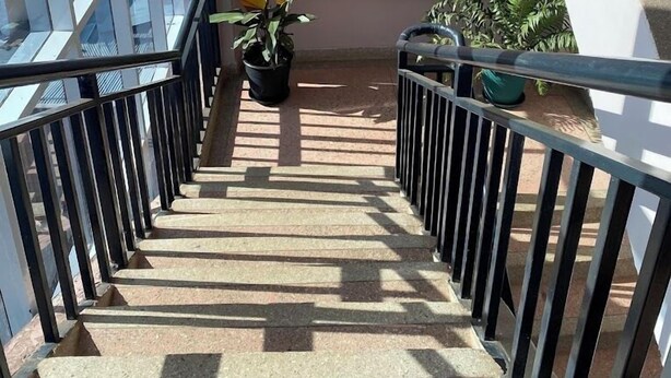 A staircase with metal railings, potted plants, and a view of the outside. - Saimo Hotel Kabarnet (Kabarnet)