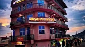 A multi-story building with balconies, signage for 'SAIMO PLAZA' and 'SAIMO HOTEL', and a street with pedestrians and parked motorcycles. - Saimo Hotel Kabarnet (Kabarnet)
