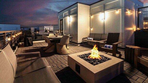 Een terras op het dak met vuurkorf, zitplaatsen en sfeerverlichting.