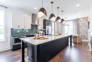Une cuisine moderne dotée d’un îlot central, de luminaires suspendus et d’un papier peint à motifs.